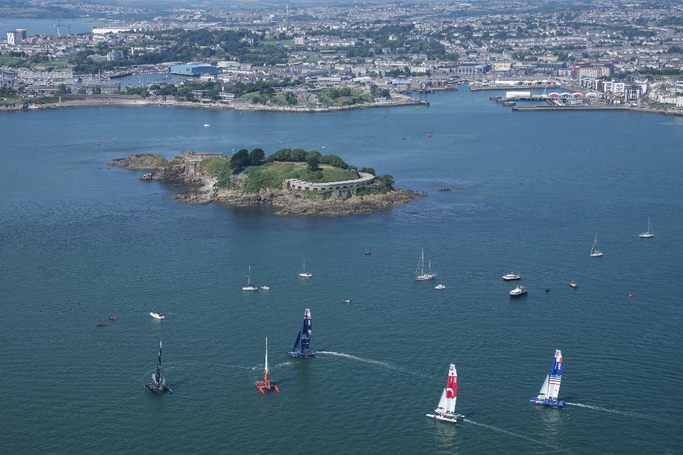 SailGP F50 catamarans sailing in Plymouth Sound against a backdrop of Drake's Island and the city in the distance